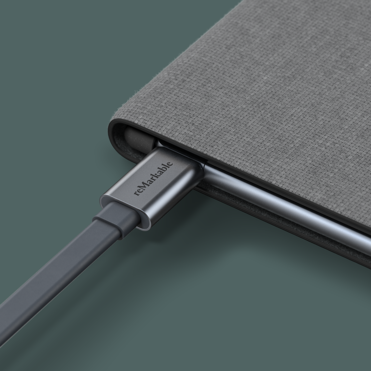 Close-up of a charging cable plugged into a Remarkable tablet, on a green surface.