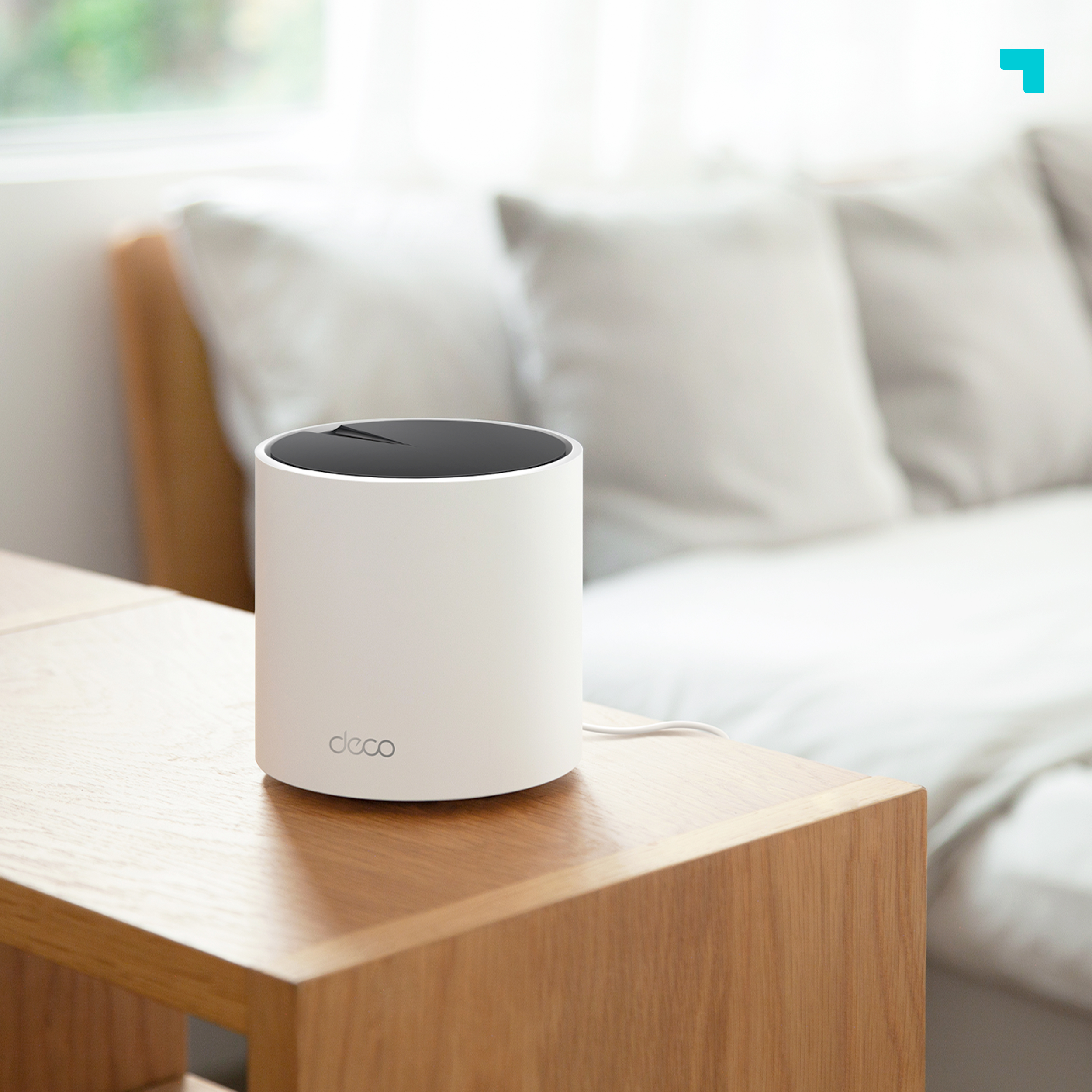 Router blanco sobre una mesa de madera. Sofá blanco en el fondo.