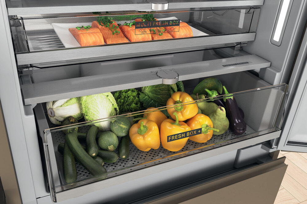 Wnętrze lodówki ze świeżymi produktami i przygotowaną żywnością w szufladach.