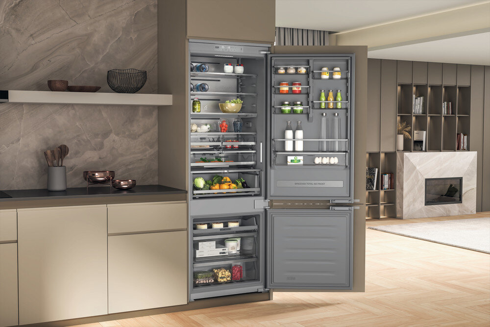 Otwarta lodówka z produktami spożywczymi, pokazująca przegrody i półki.