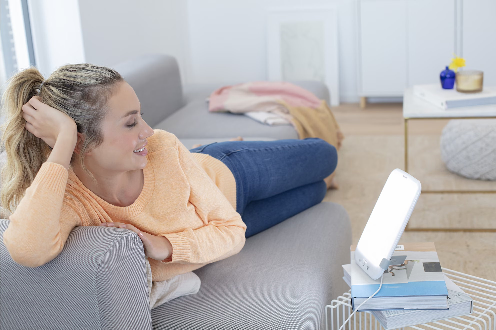 Une femme se relaxant sur un canapé, utilisant un appareil de luminothérapie.