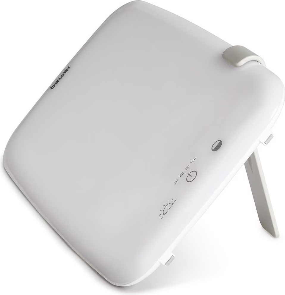 Un appareil blanc avec une surface émettant de la lumière, probablement un appareil de luminothérapie, avec des boutons et un support.