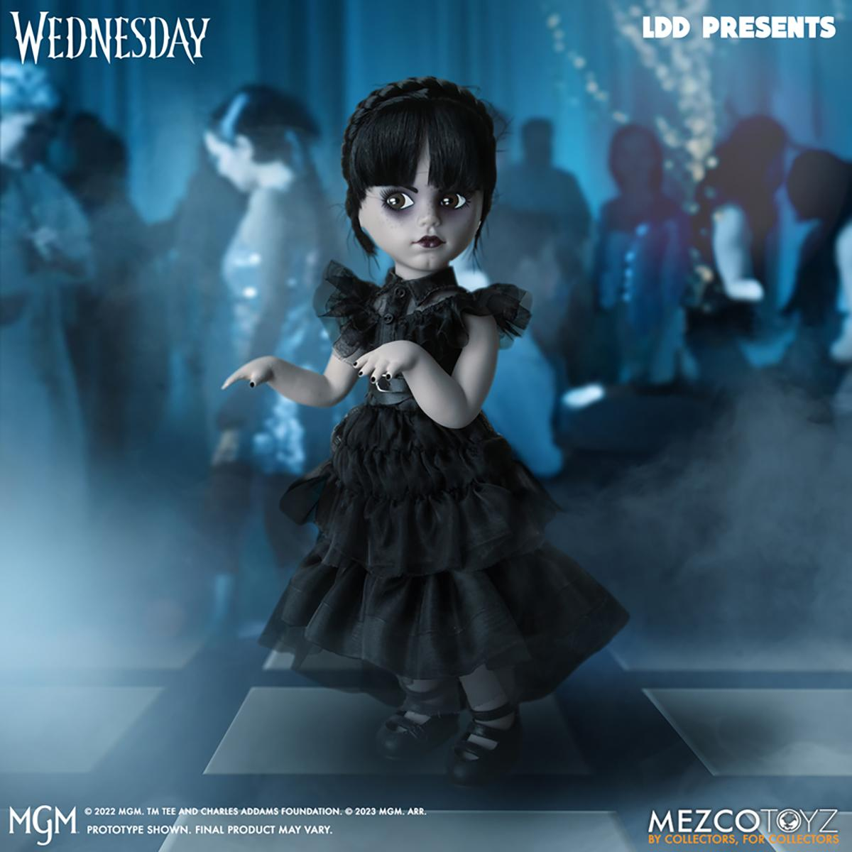 Eine Puppe von Wednesday Addams in schwarzem Kleid, die auf einer Bühne mit anderen verschwommenen Figuren steht.