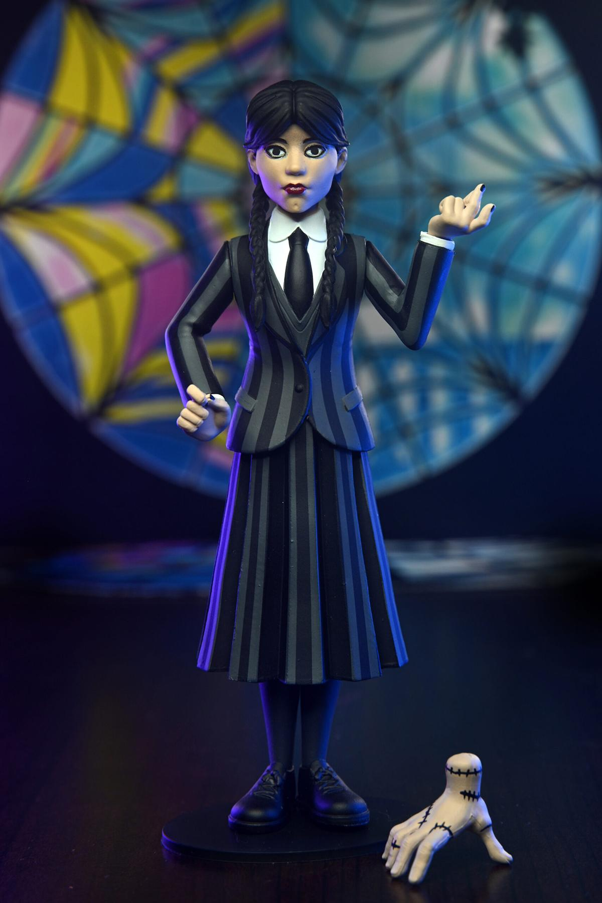 Eine Wednesday Addams-Figur in schwarz-grauem Streifenoutfit, die eine abgetrennte Hand hält.