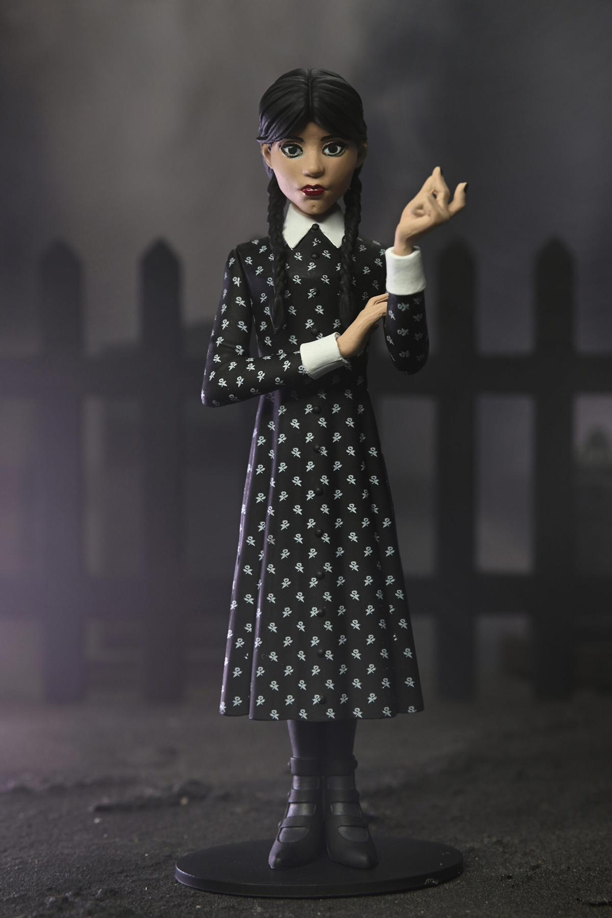 Eine Wednesday Addams-Figur in einem schwarzen Kleid, stehend.