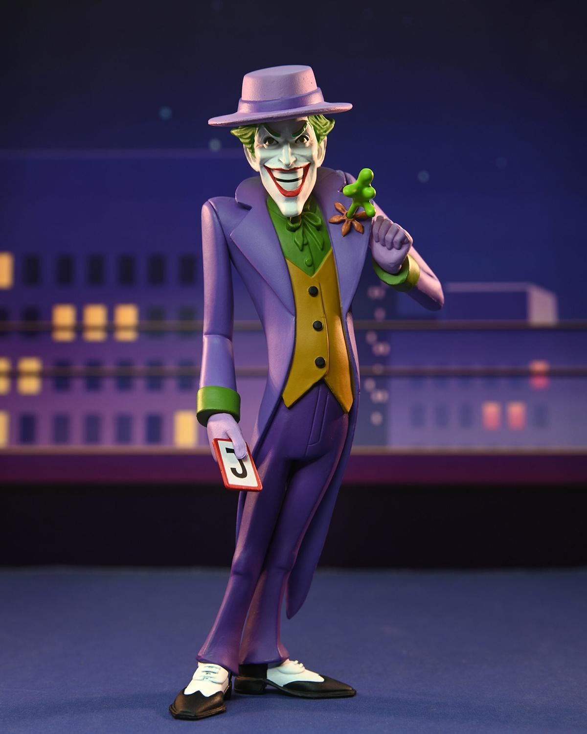 Die Joker-Figur in lila Anzug, hält eine Blume und eine Karte mit der Zahl 5, auf der Bühne.