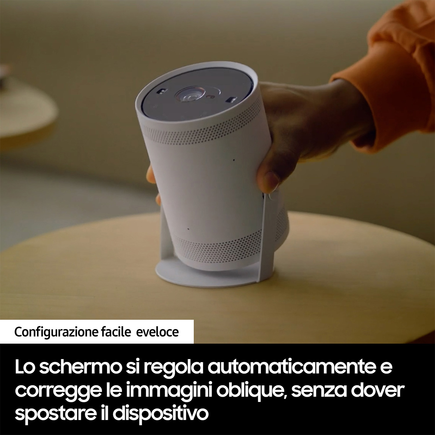 Un proiettore cilindrico bianco su un tavolo di legno. Una mano nera lo regola. Il testo lo descrive.