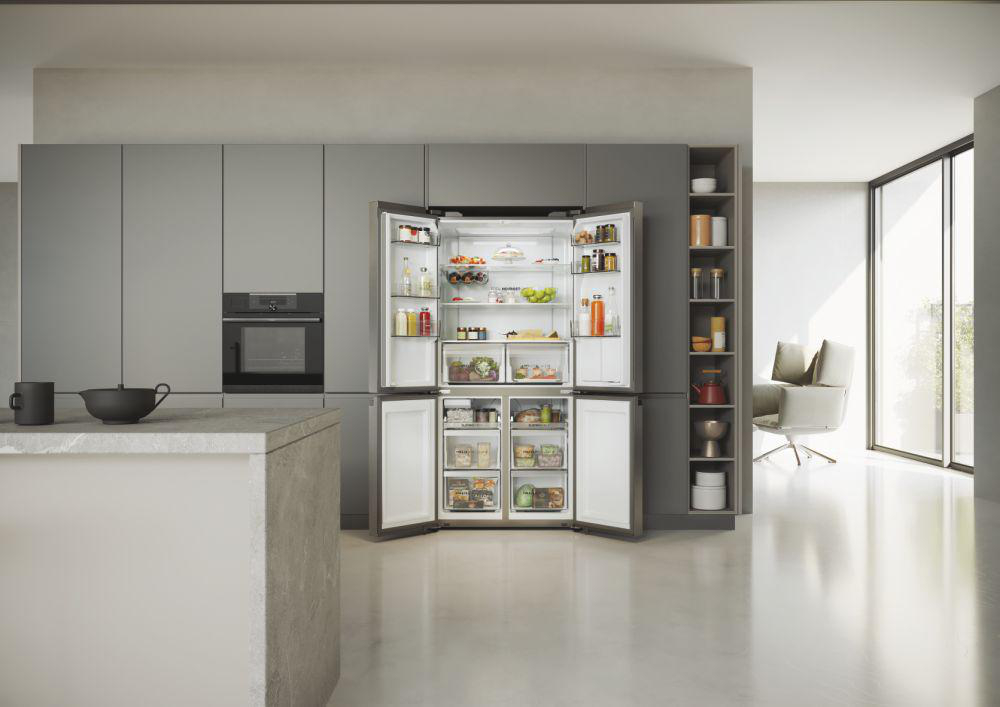 Moderne Küche mit geöffnetem großem Kühlschrank, gefüllt mit Lebensmitteln. Graue Schränke und eine weiße Insel.