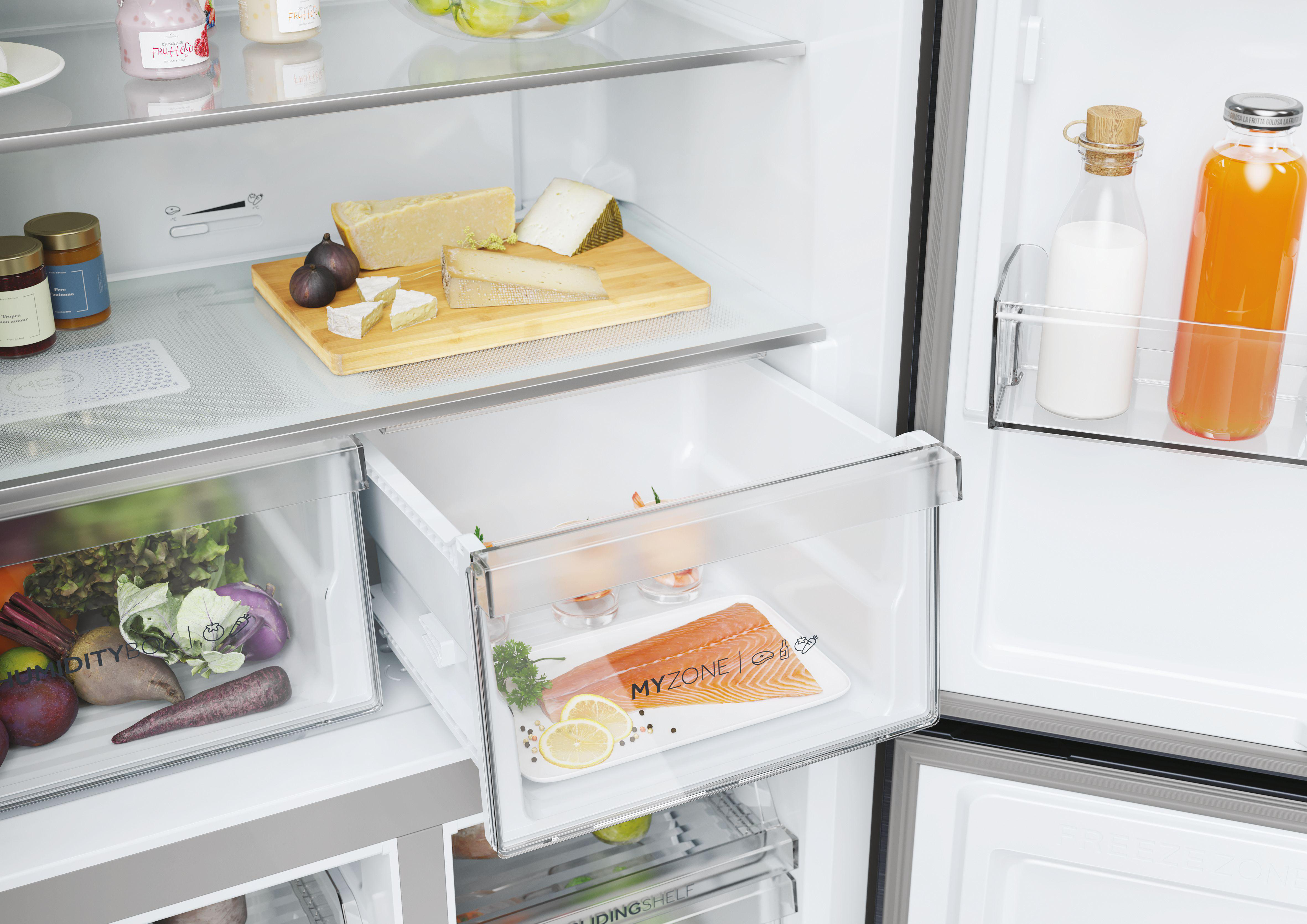 Kühlschrank-Innenraum. Käse, Trauben, Lebensmittel. Schublade mit Lachs, Zitrone und Petersilie.
