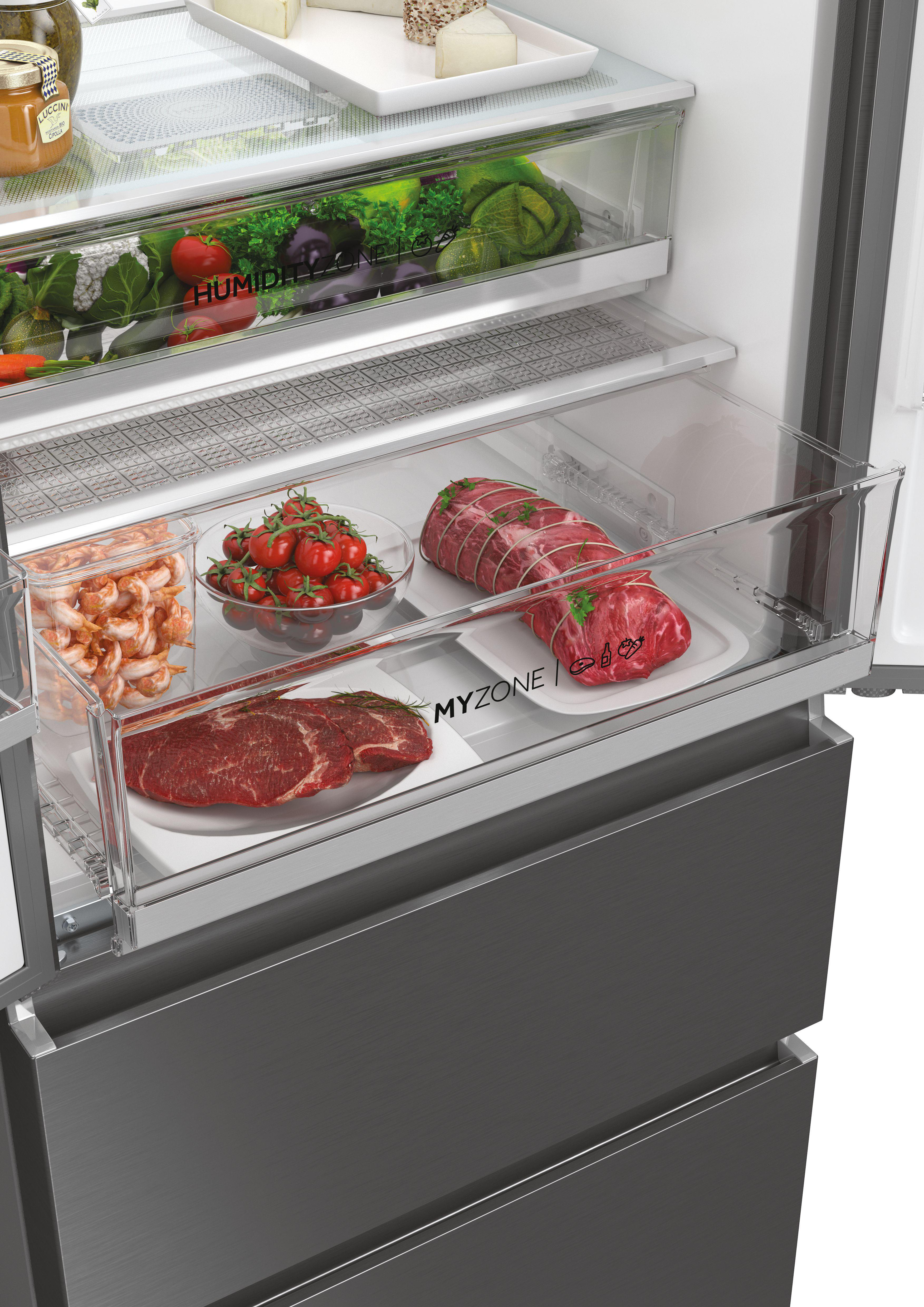 Kühlschrank-Innendetail mit Lebensmittelschubladen. Enthält Garnelen, Tomaten, Steaks und Braten. Mit 'My Zone'.