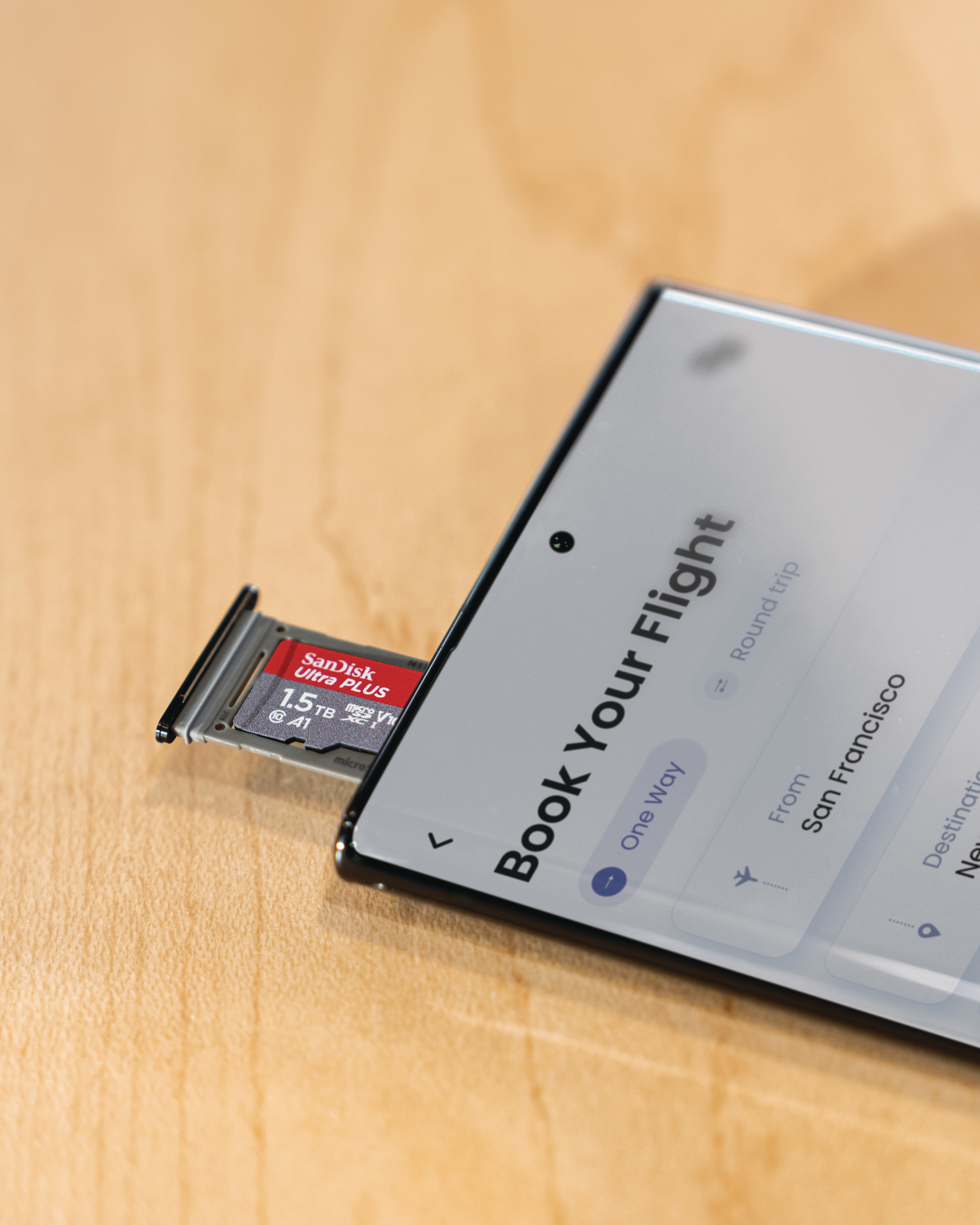 Ein Telefon mit geöffnetem SD-Kartensteckplatz und eingelegter SD-Karte, Holzgrund.