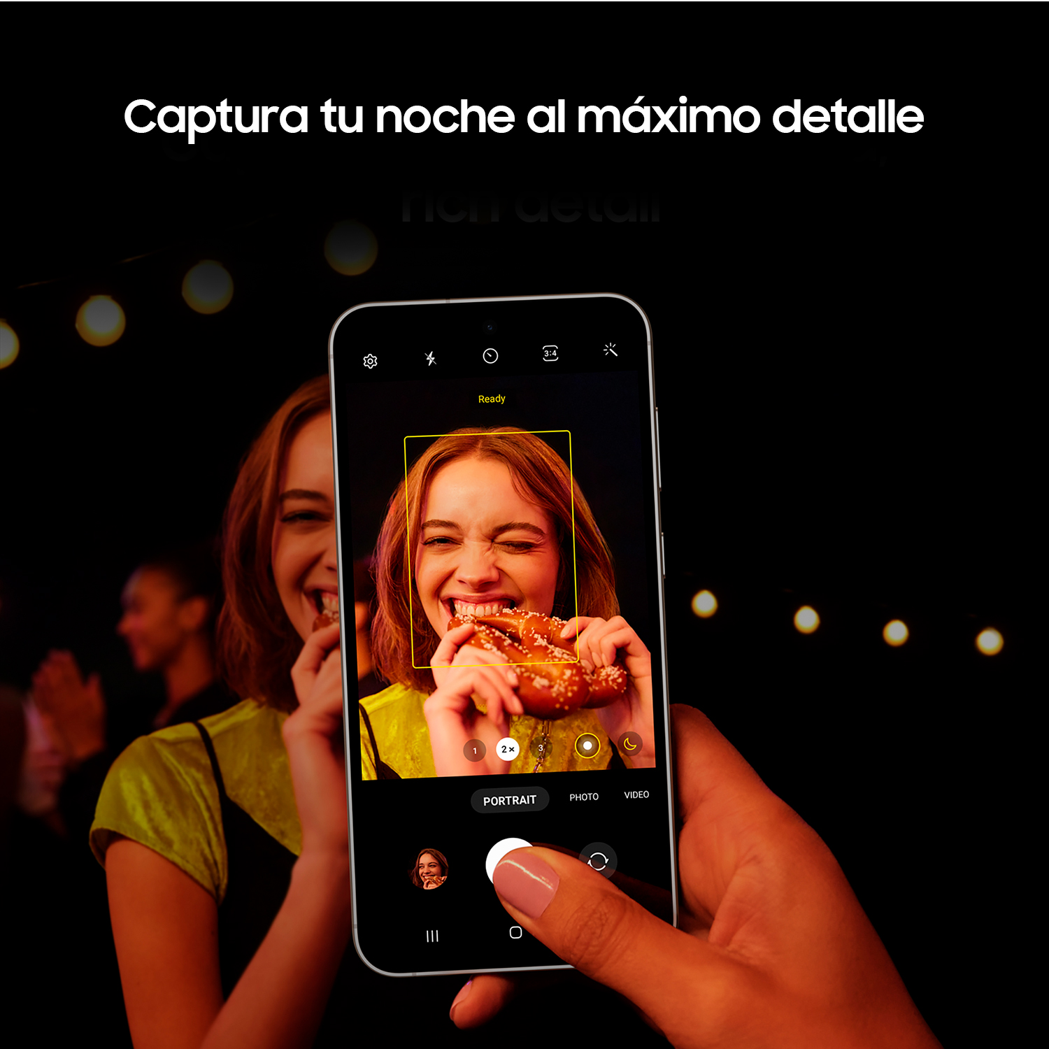 Persona tomando fotos a otra comiendo un pretzel. Teléfono en mano, borde amarillo en la pantalla.
