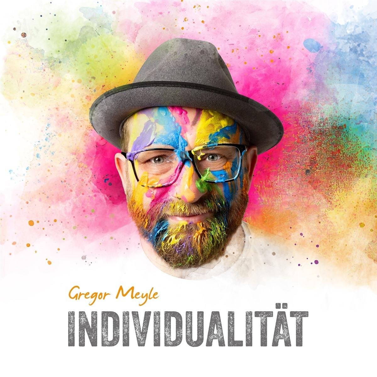 Porträt eines Mannes mit bunter Farbe im Gesicht und einem grauen Hut, mit Text.