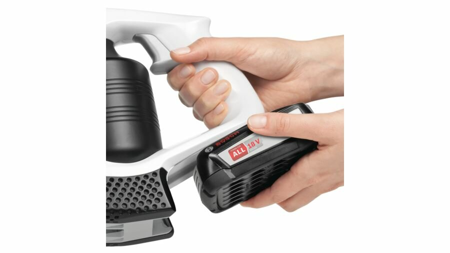 Ręce osoby mocującej czarną baterię do biało-czarnego odkurzacza.