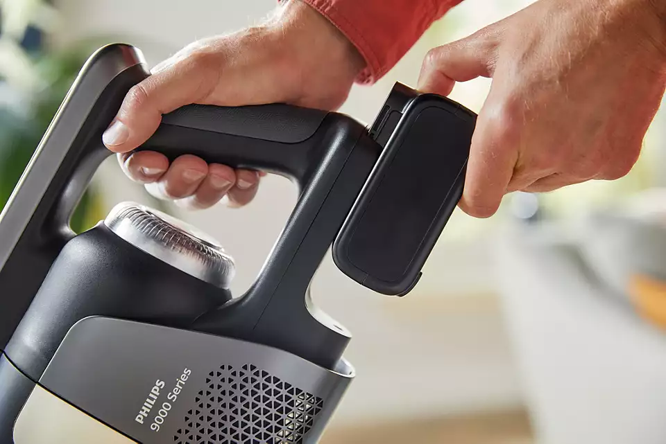 Ręce trzymające szary i czarny uchwyt odkurzacza Philips serii 9000.