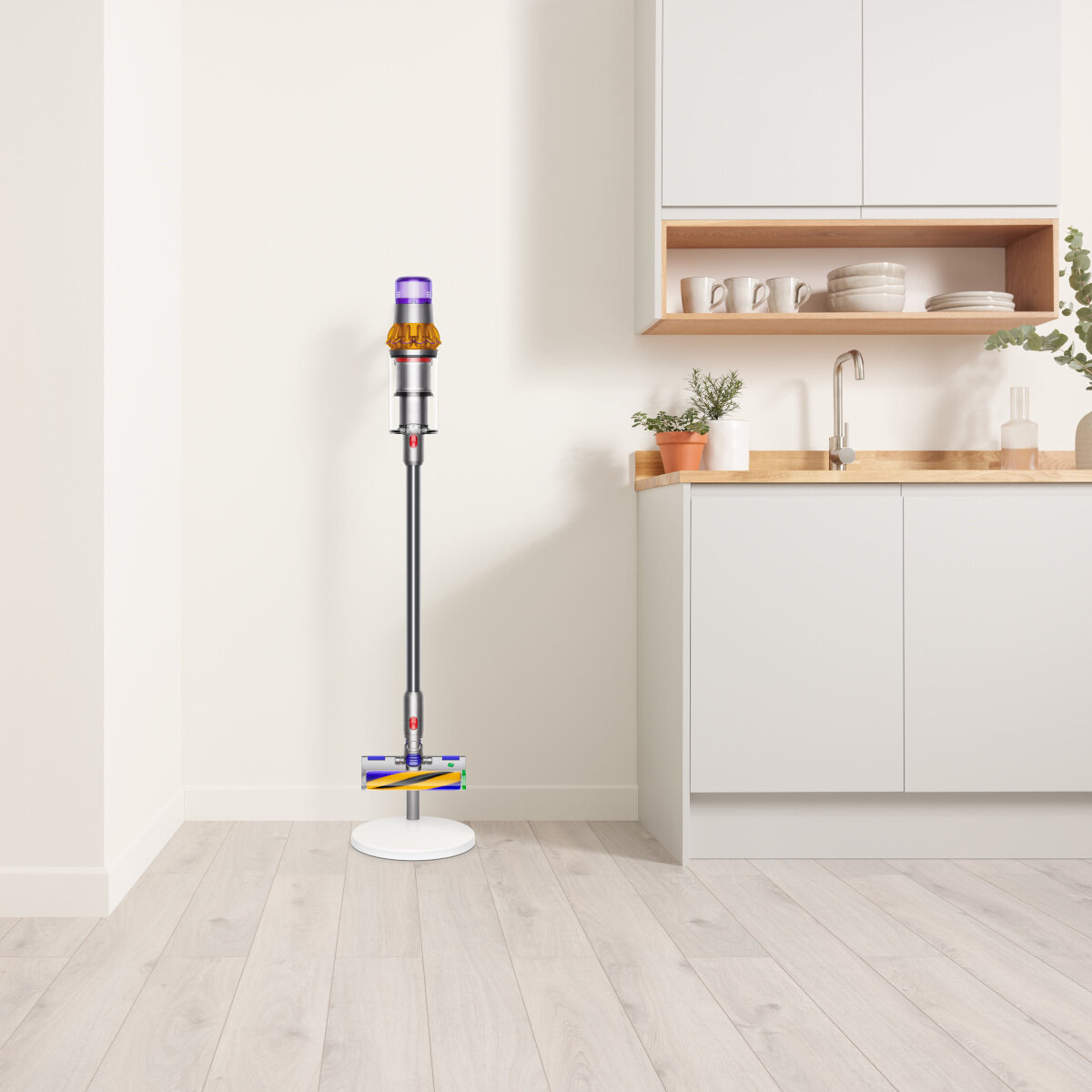 Biały odkurzacz Dyson stoi na białej podstawie w rogu pokoju.