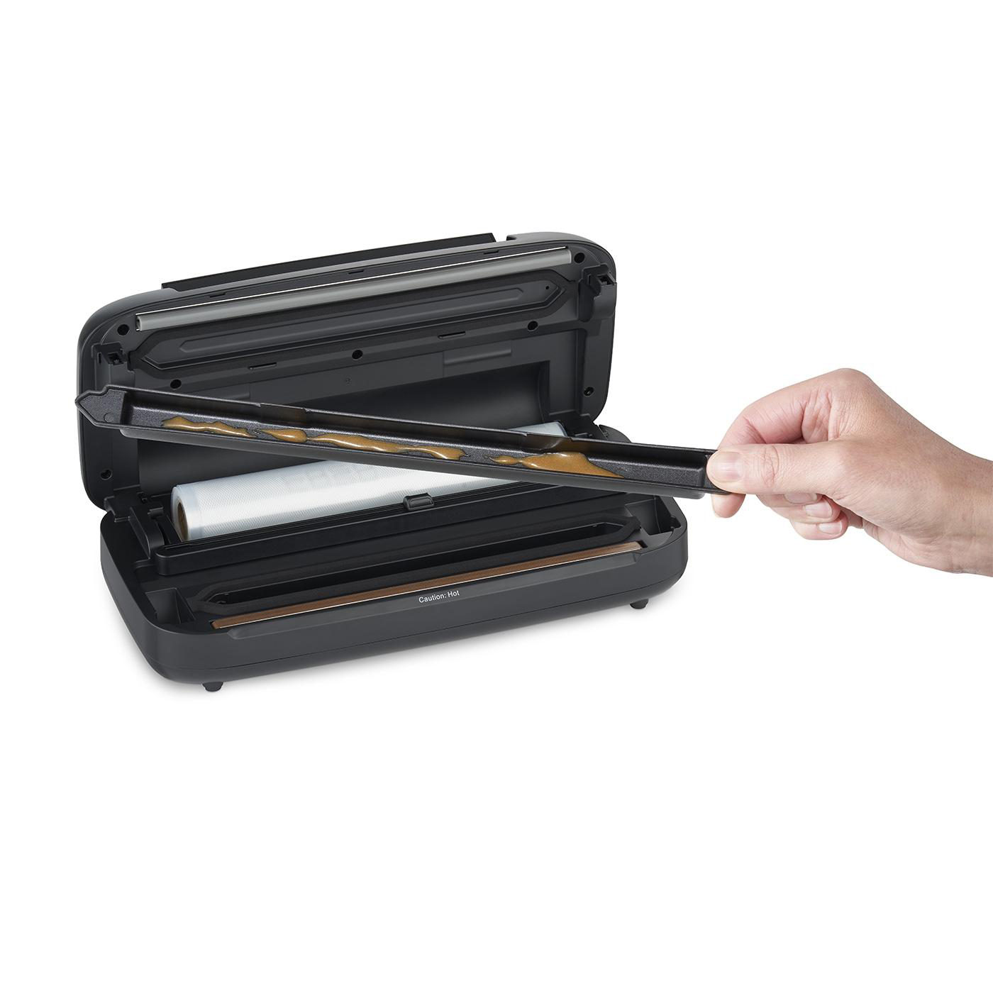 Der Vakuumierer ist geöffnet, und eine Hand entfernt ein Tablett.