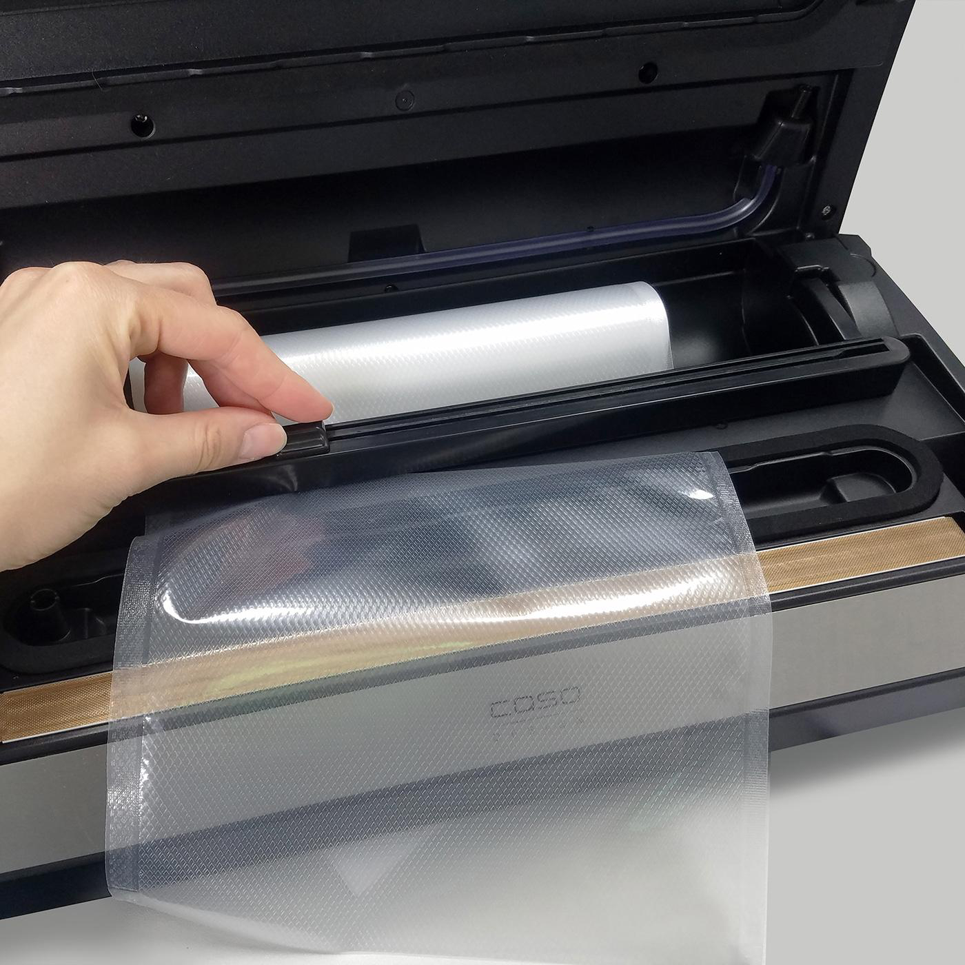 Eine Hand, die einen Vakuumbeutel hält, mit einem Vakuumiergerät im Hintergrund.