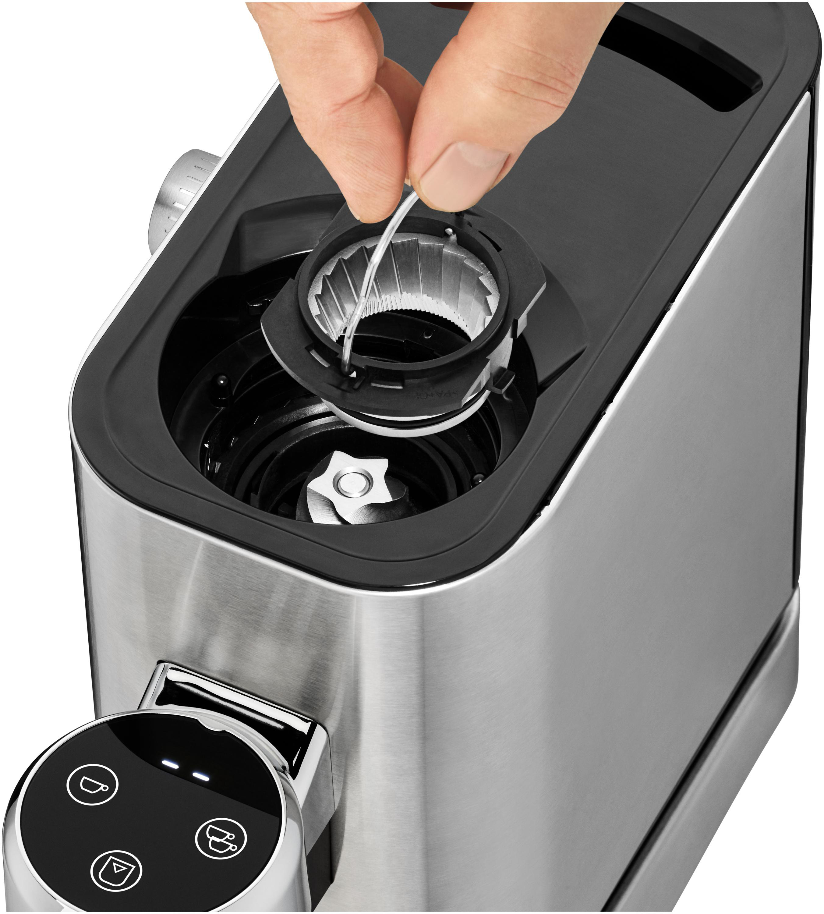 Eine Hand setzt einen Filter in eine Kaffeemühle ein. Die Mühle ist silber und schwarz.