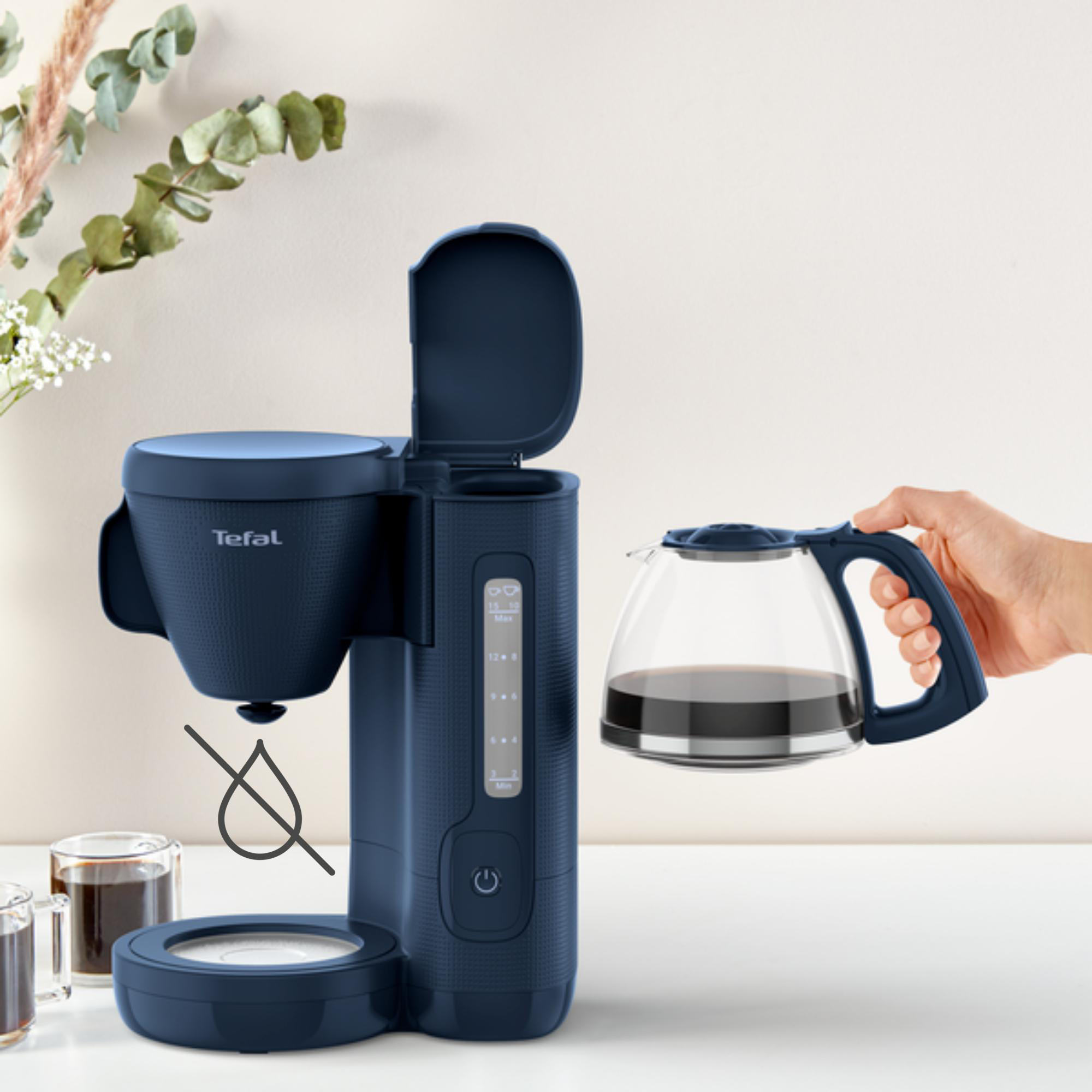 Ein blauer Kaffeebereiter mit der Karaffe, die in der Hand gehalten wird.