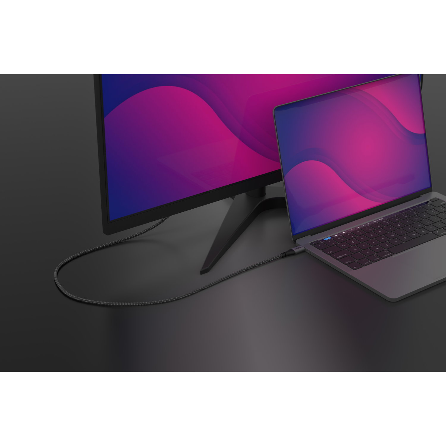 Laptop connected to a monitor with a cable. The monitor and laptop are on a black surface.
