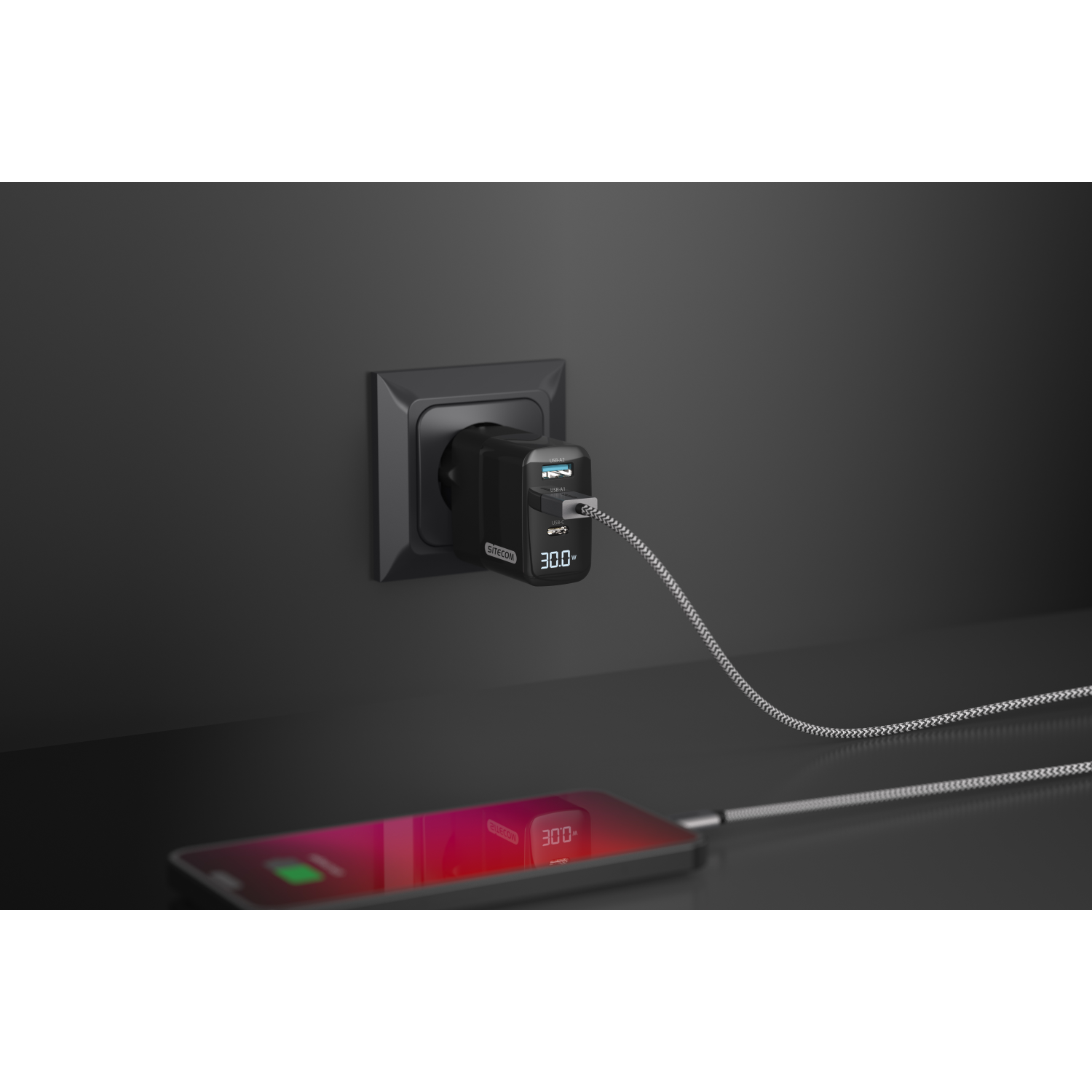 A phone charging with a black charger plugged into a wall socket.