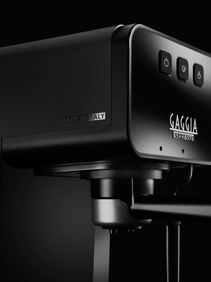 Fekete Gaggia eszpresszógép, közelkép. Made in Italy felirat látható. Fekete háttér.