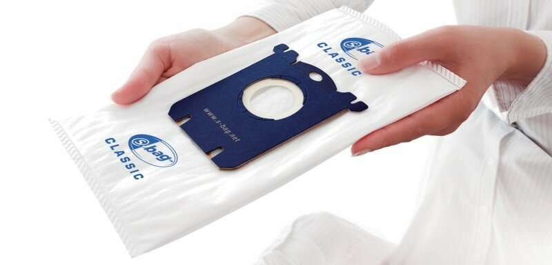 Osoba trzymająca worek do odkurzacza z niebiesko-białym wzorem.