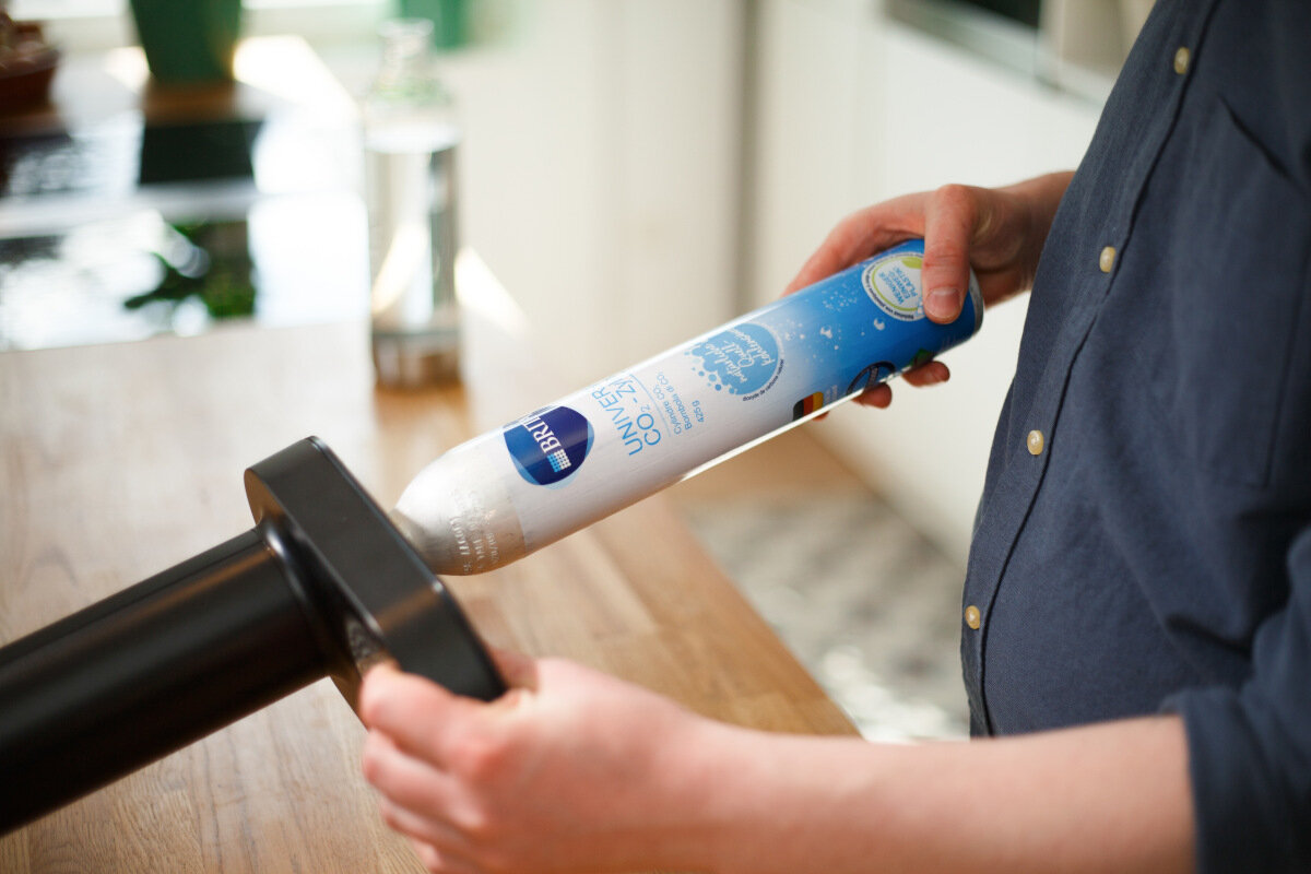 Osoba trzymająca wkład filtrujący Brita. Wkład jest biało-niebieski, tłem jest stół.