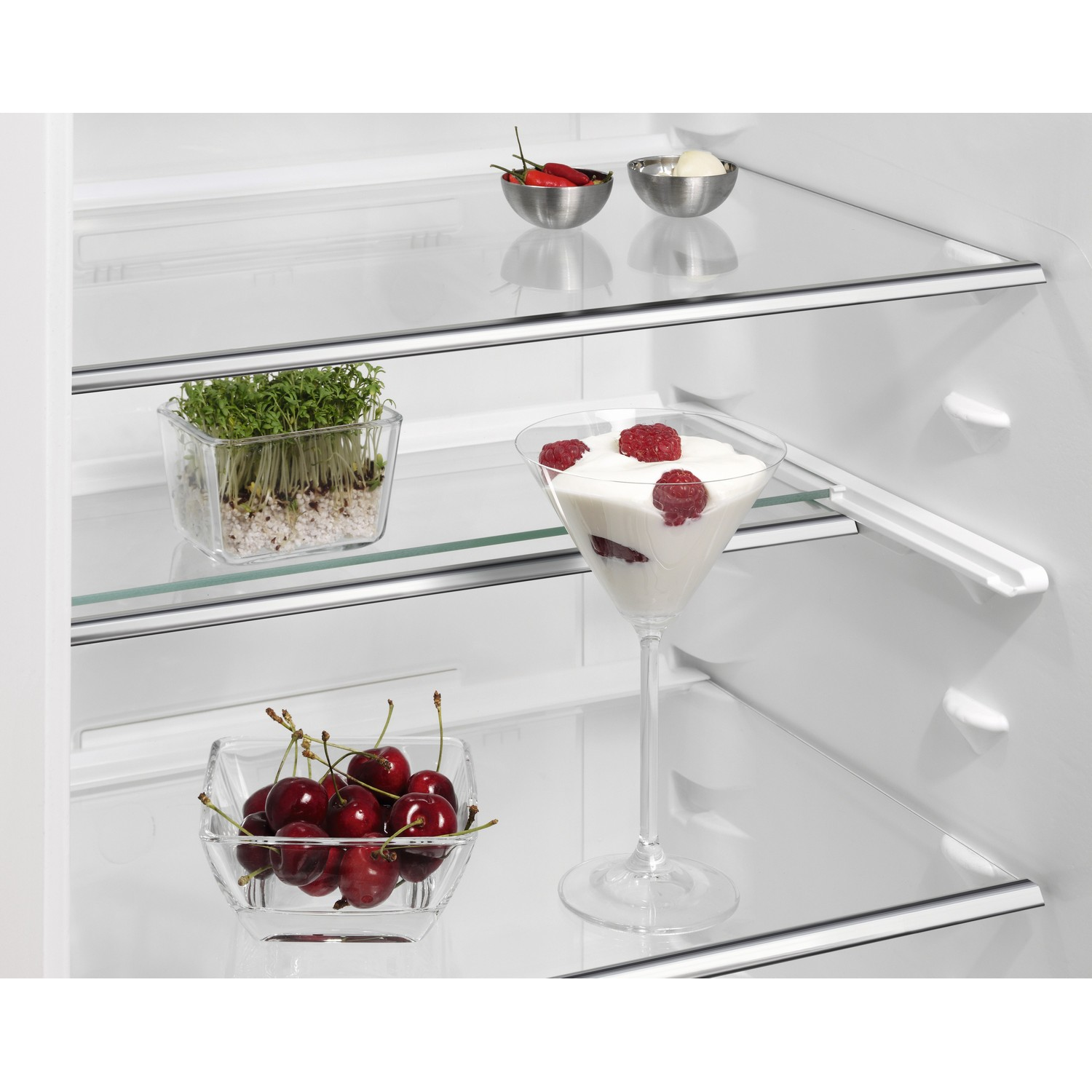 À l'intérieur d'un réfrigérateur: légumes, cerises, framboises dans un verre à martini et autres aliments.