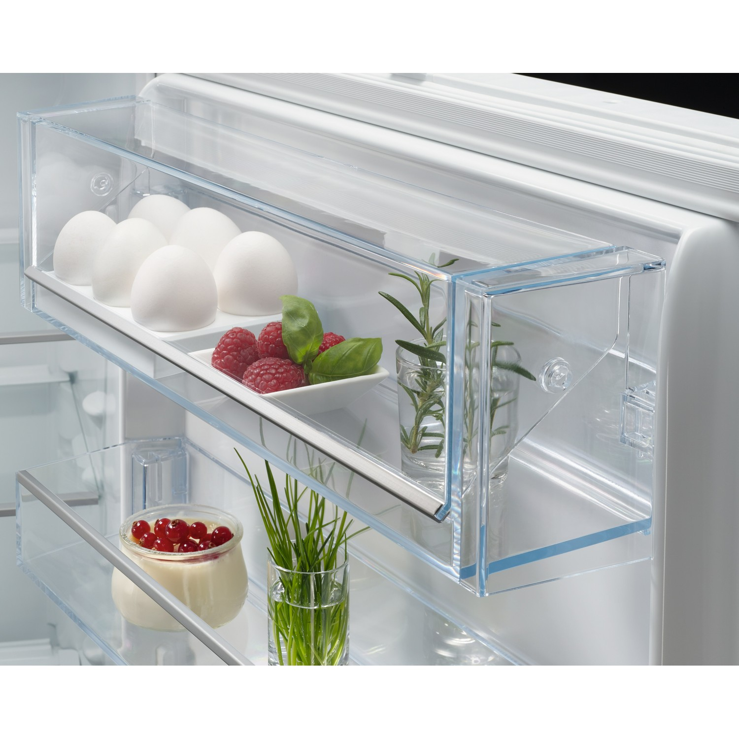 Intérieur de réfrigérateur avec œufs, framboises, basilic et groseilles dans récipients.