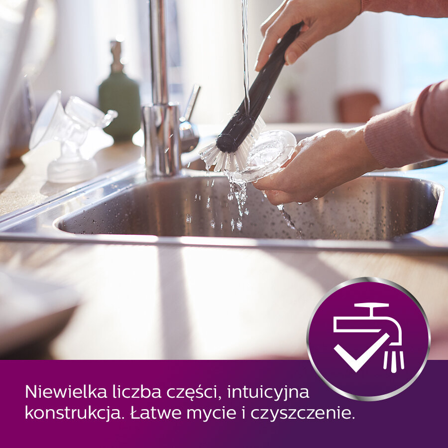 Ręka szoruje szklankę pod bieżącą wodą w zlewie za pomocą szczotki.