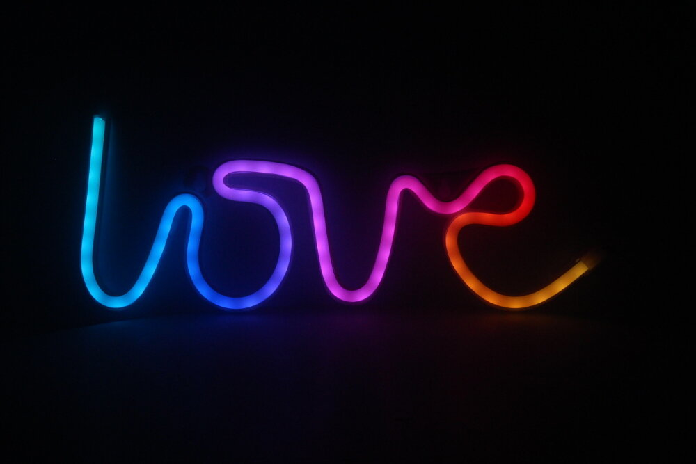 Neonowy napis słowa 'love' w wielu kolorach.