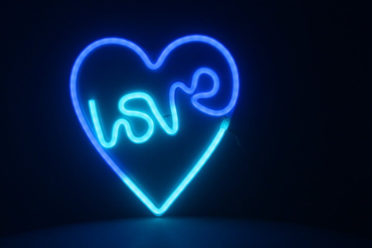 Niebieskie neonowe serce z napisem 'love' w środku na czarnym tle.