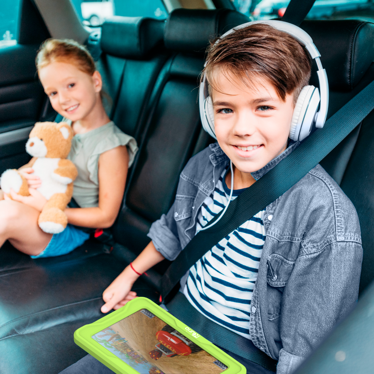 Twee kinderen in autostoeltjes, een met een koptelefoon, kijken naar een tablet met een autoracespel.