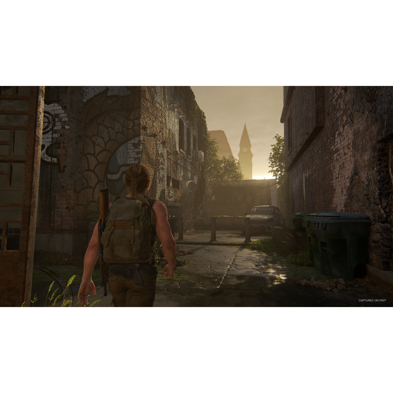 A person walks in a dark alley with buildings on both sides, the sun is shining.
