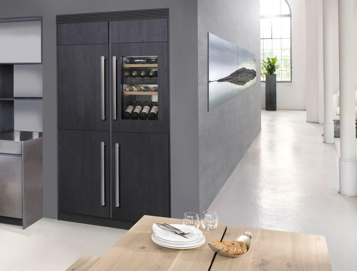 Eine moderne Küche mit dunklem Holz-Kühlschrank, Weinkühler und Tisch mit Gedecken.