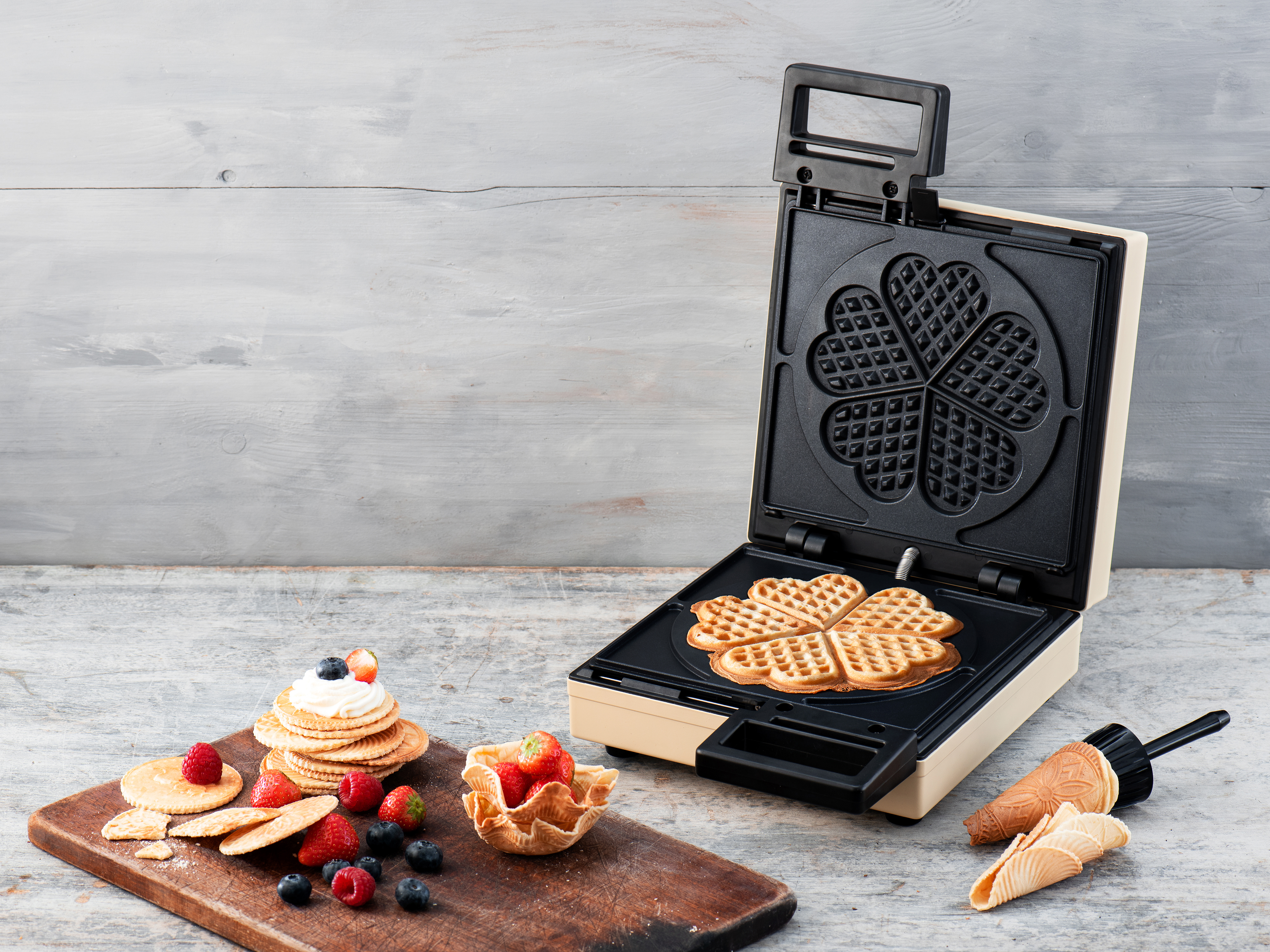 Una piastra per waffle aperta con waffle e frutta finiti.
