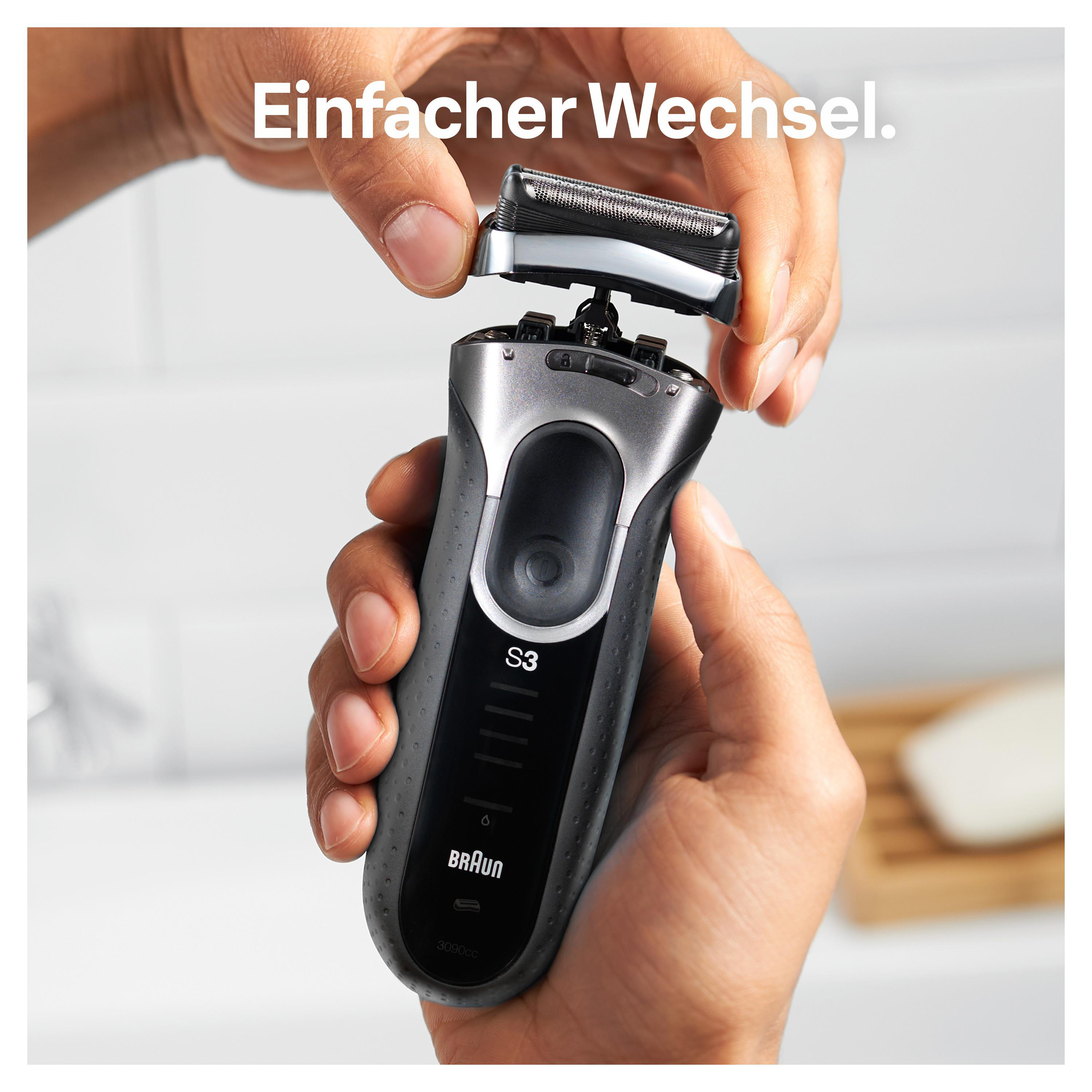 Eine Person wechselt den Kopf eines elektrischen Rasierers. Der Rasierer ist schwarz und silber.