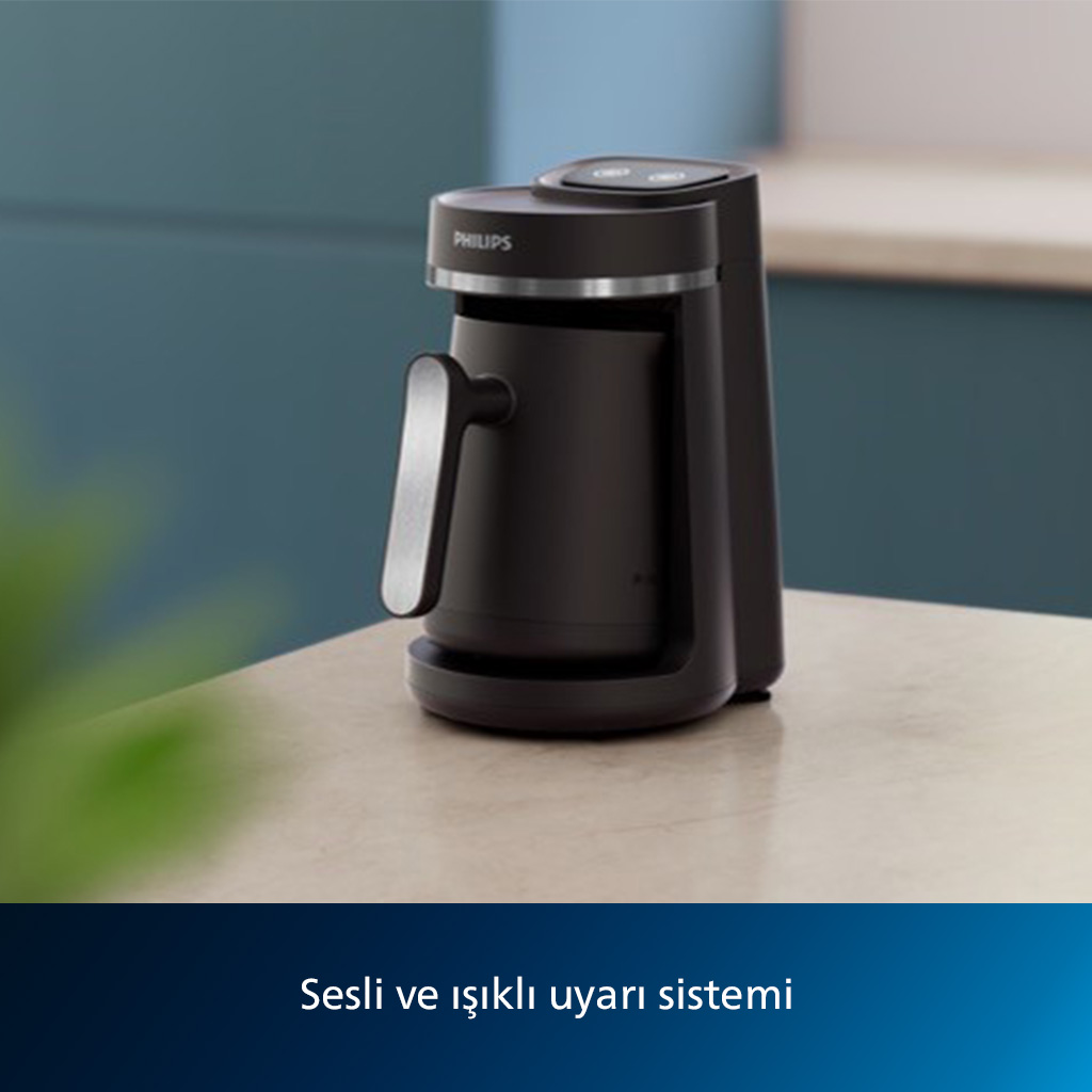 Siyah Philips kahve makinesi masada, bulanık mavi ve yeşil bir arka plan ile.