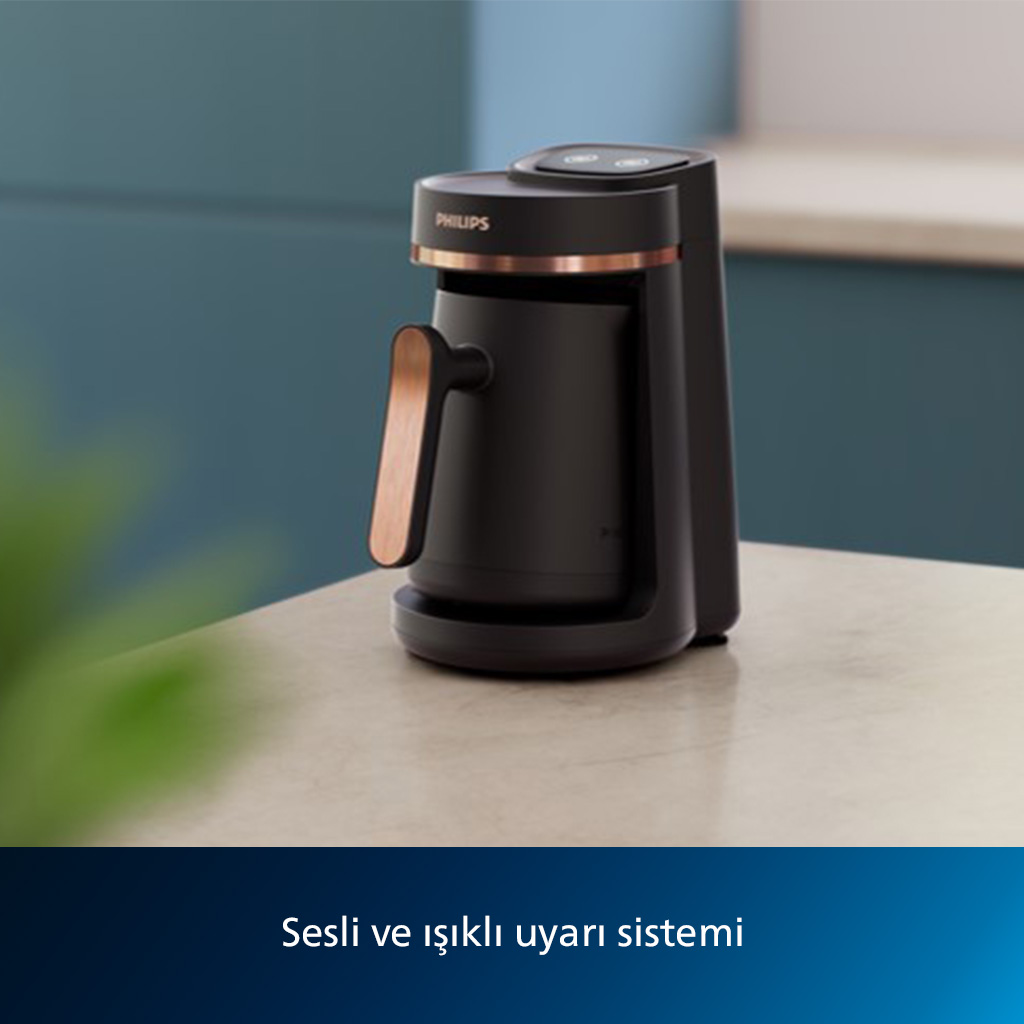 Bir masada bakır detaylı siyah bir kahve makinesi.