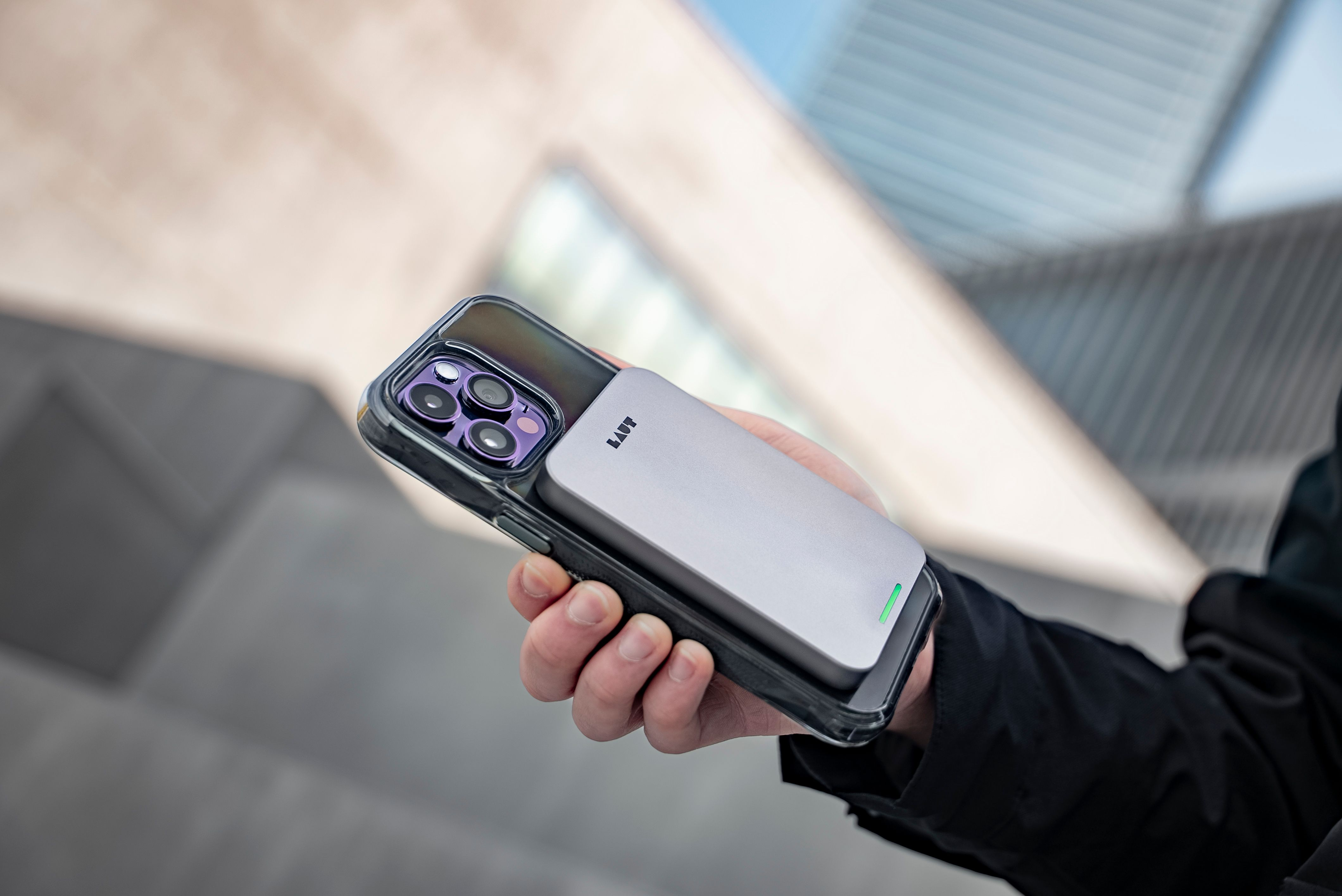 Eine Hand, die ein Telefon mit einer Hülle hält, an der ein Ladepack befestigt ist.