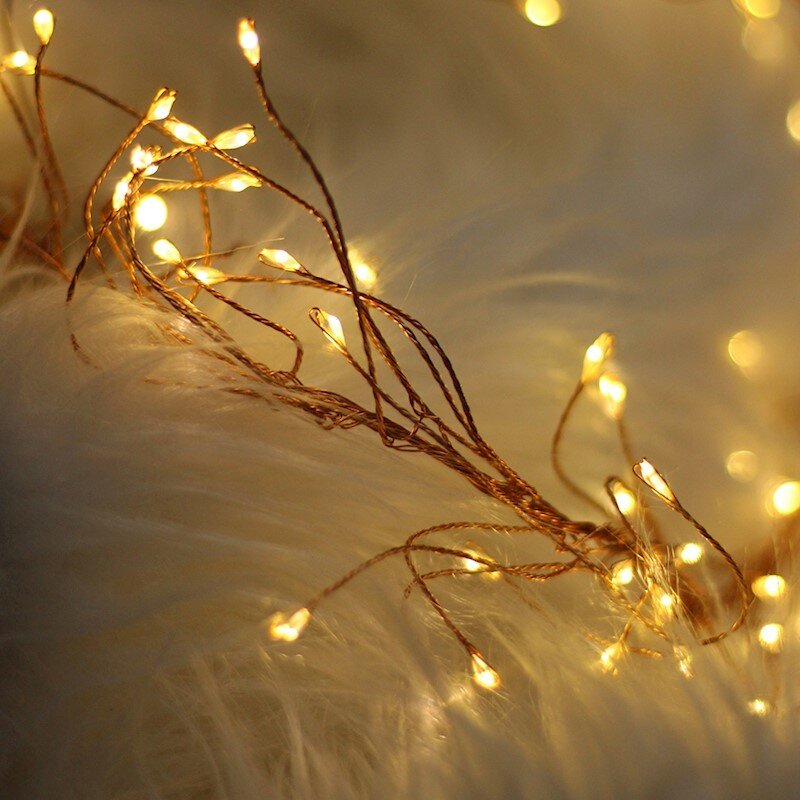 Zbliżenie ciepłych lampek choinkowych na białej, puszystej powierzchni.