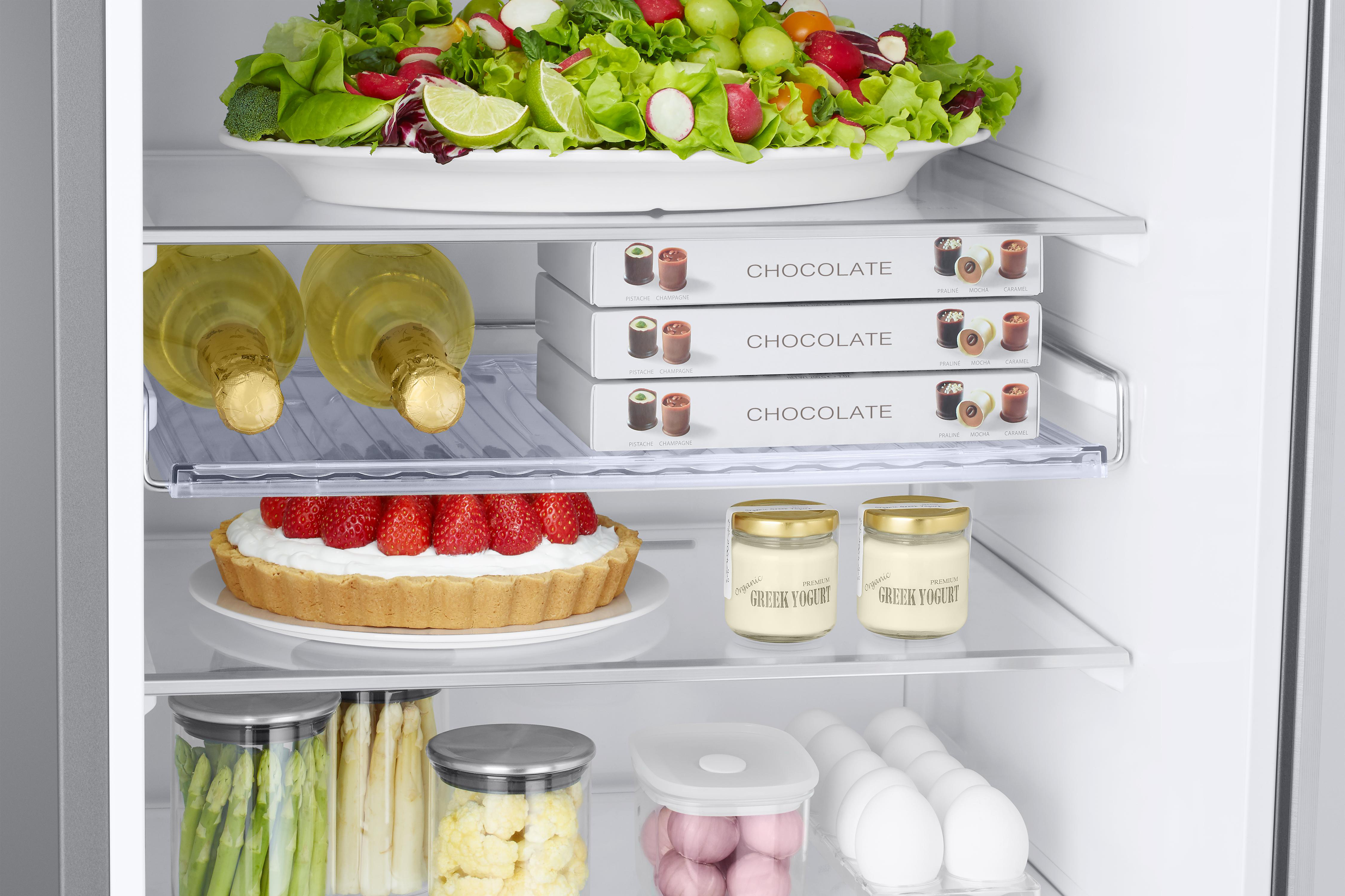 Kühlschrankinnenraum: Salat, Champagner, Pralinen, Kuchen, Joghurt, Eier und Gemüse.