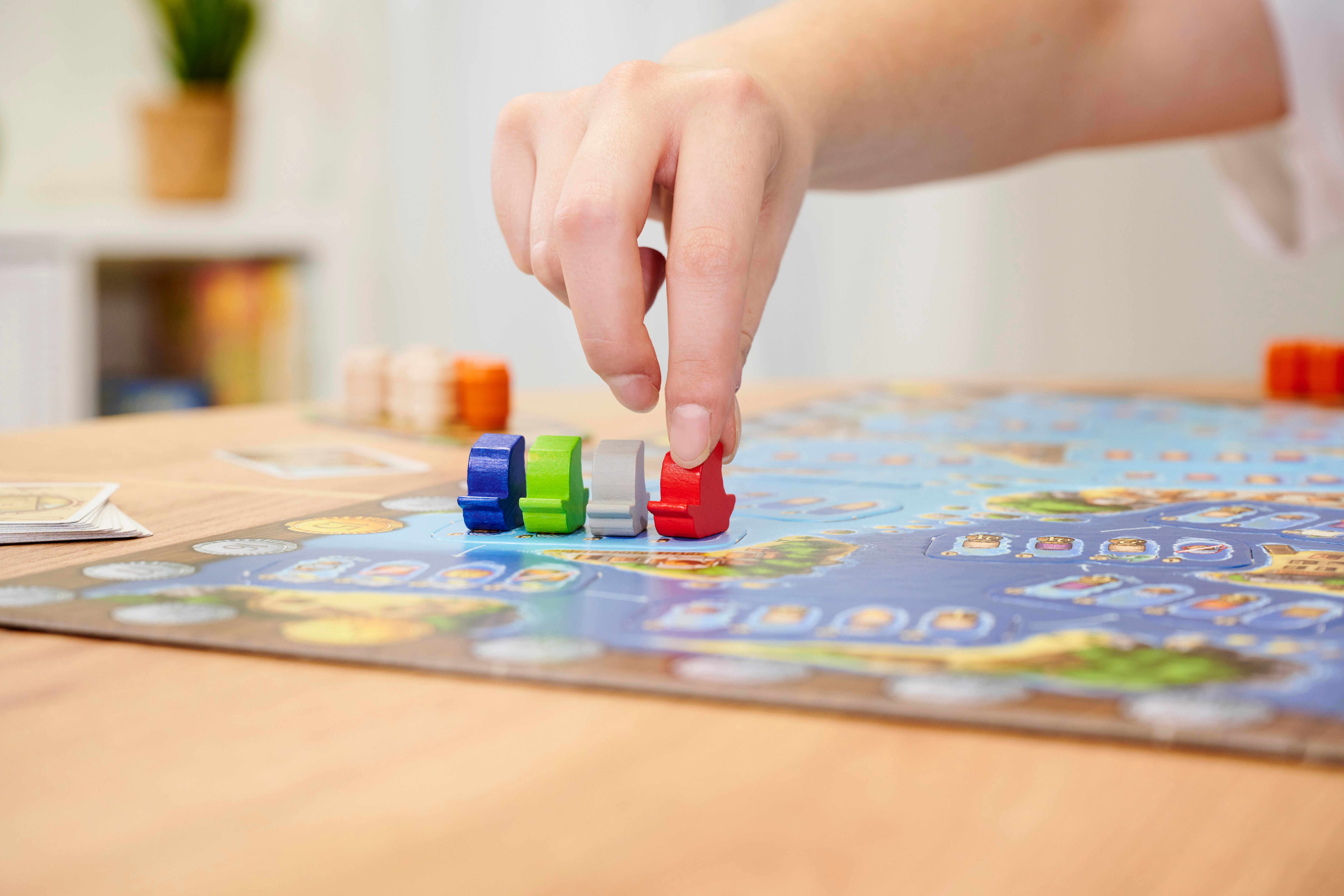 Eine Hand, die ein rotes Spielteil auf ein blaues Brett legt, mit anderen sichtbaren Teilen.