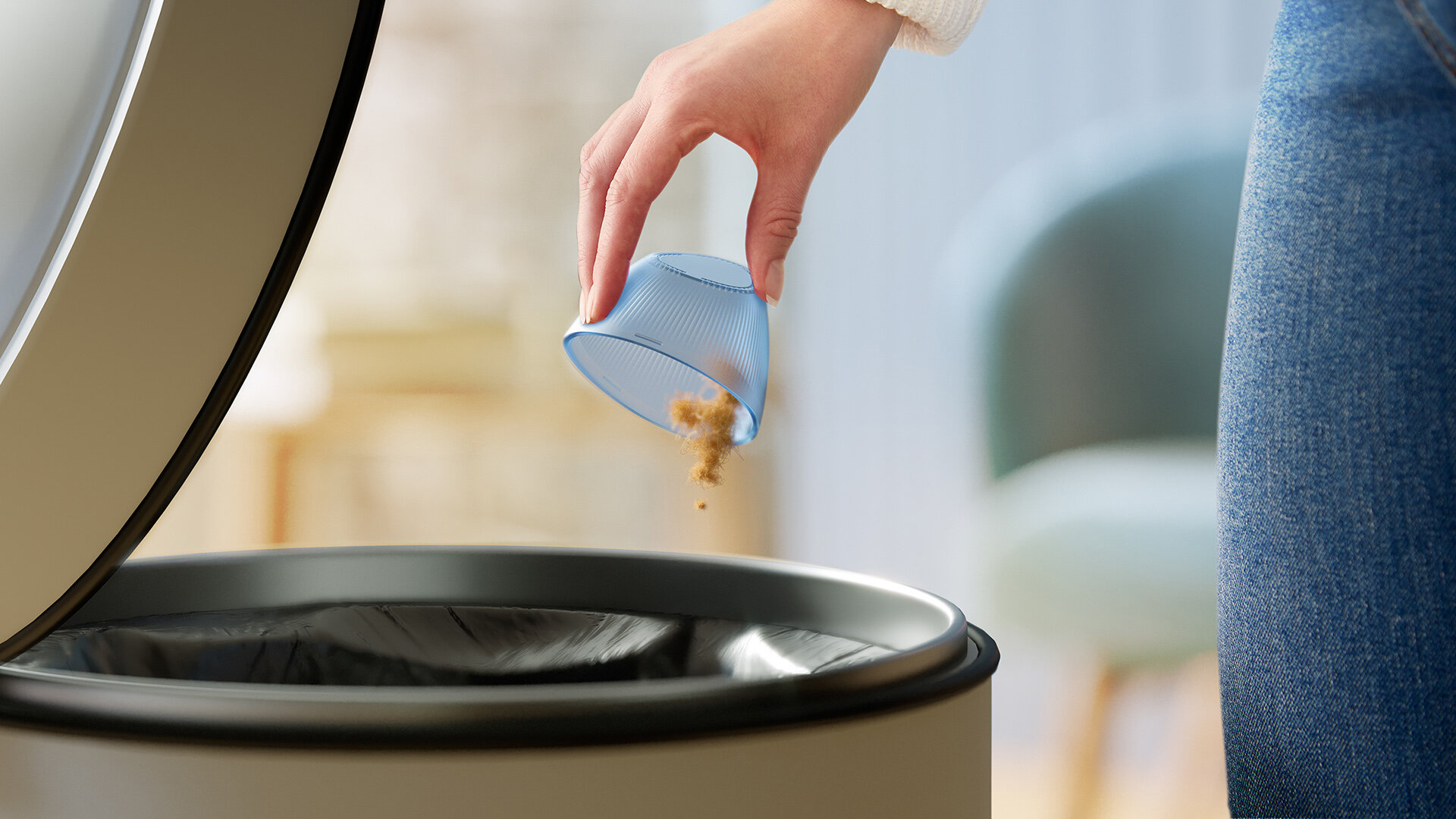 Ręka wsypująca pył z niebieskiego kubka do czarnego kosza na śmieci.