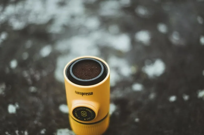 Sárga Nanopresso kávéfőző, a tetejét mutatja, benne őrölt kávéval.