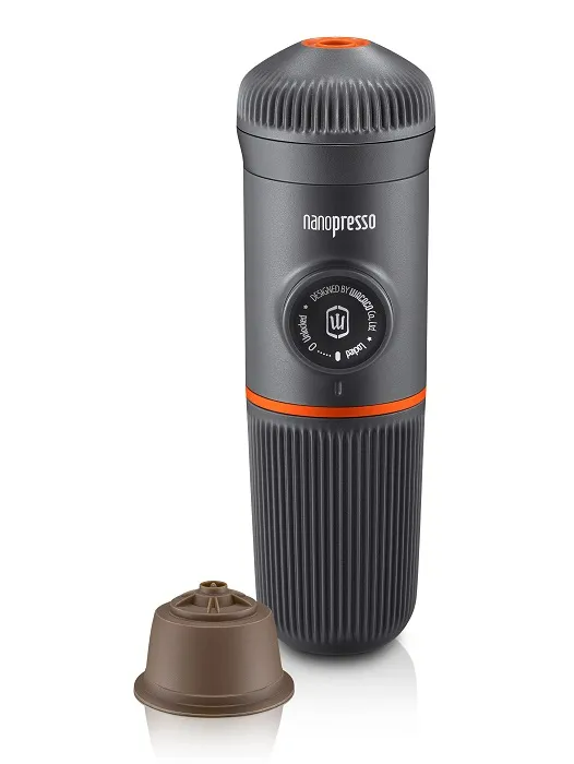 Egy sötétszürke Nanopresso kávéfőző, narancssárga szalaggal és barna kapszulával.