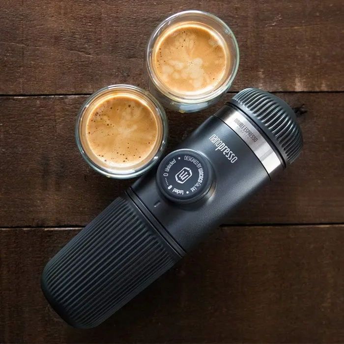 Két kis kávés pohár és egy Nanopresso kávéfőző egy faasztalon. Felülnézet.