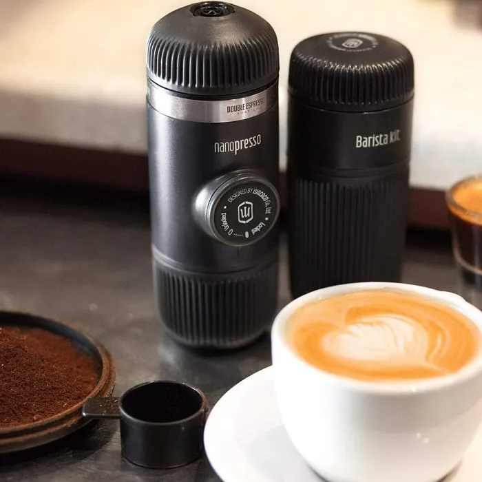 Fekete Nanopresso és Barista Kit egy csésze latte-val és kávézacc-cal az asztalon.